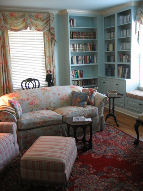 This library show off the homeowners antiques and fine rug; a comfortable sofa is slipcovered in rose printed linen.
